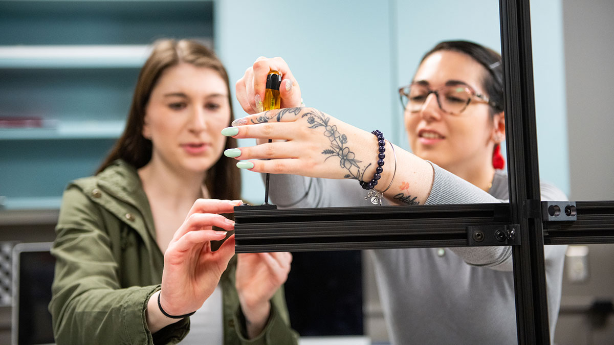 two students tightening a bracket with a screwdriver.