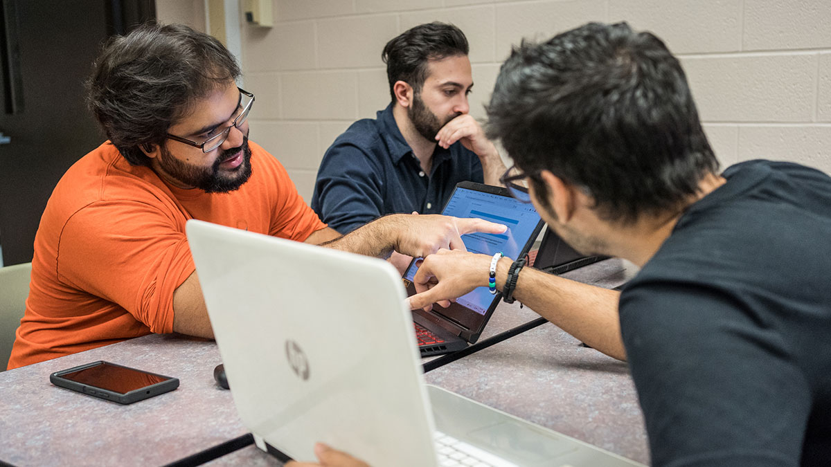 students pointing to a laptop screen.