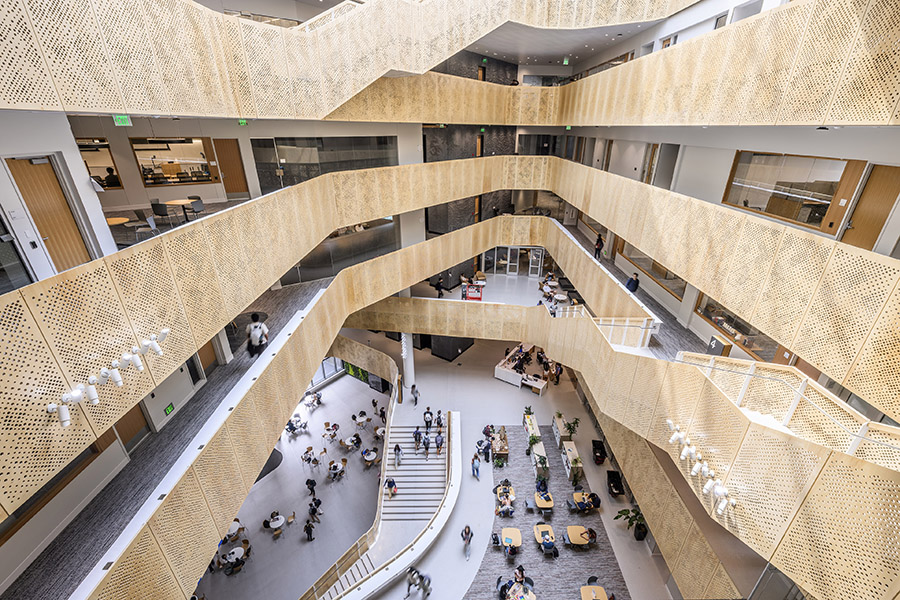 panorama of a stairwell overlooking a courtyard with people seated at tables