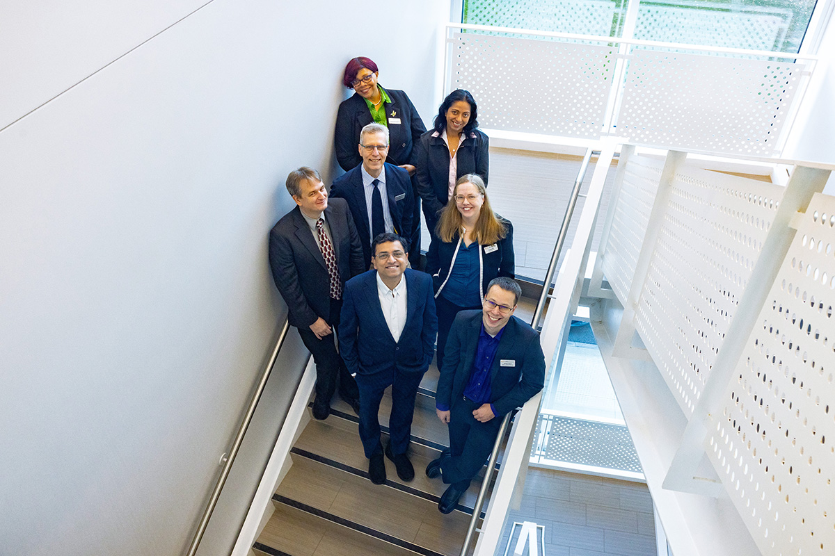 Photo of several people posing in a stairwell, looking up towards the photorgrapher.