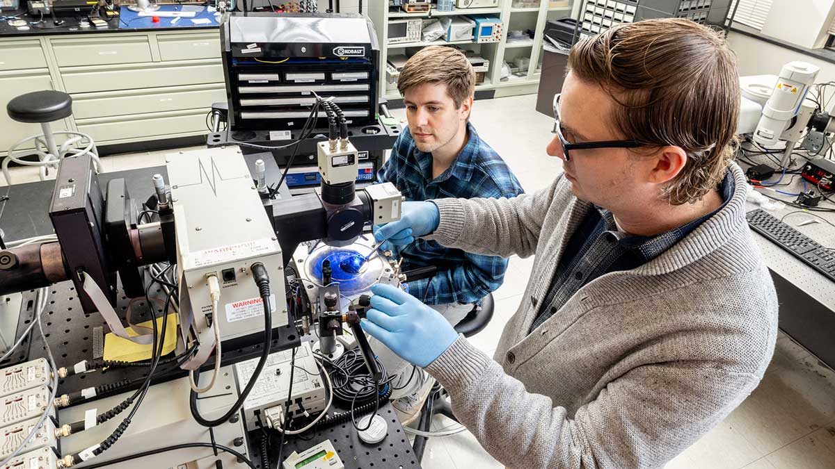 two P H D students working with semiconductor machinery.