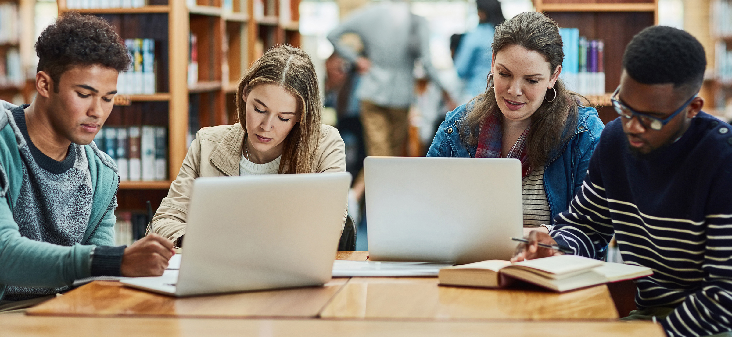 students sitting at table and working on their laptops