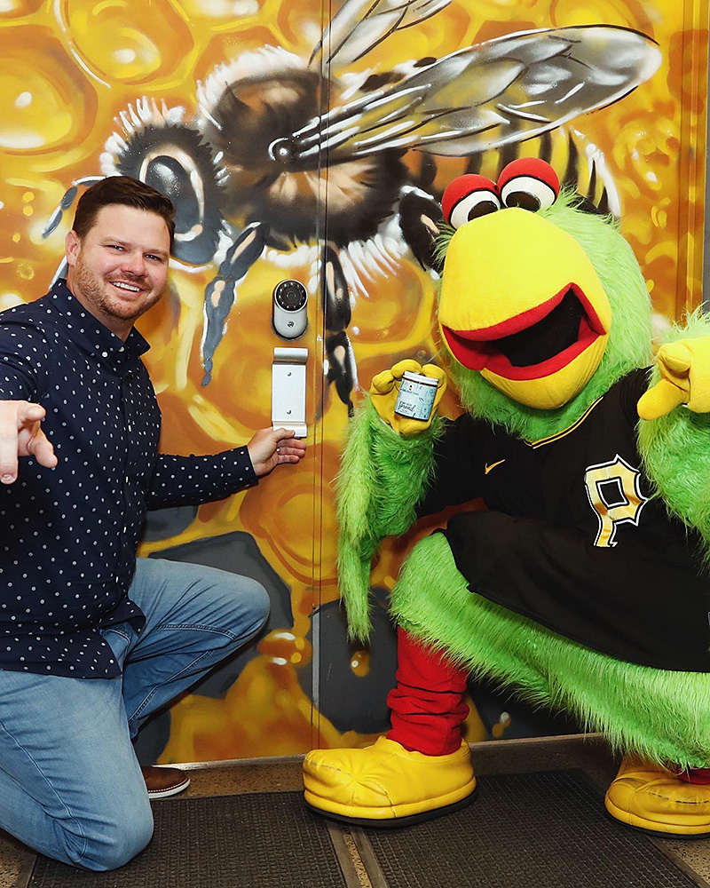 Photo of Jon Mosholder posing with the Pittsburgh Pirates mascot, who is holding a jar from Bumbleberry Famrs