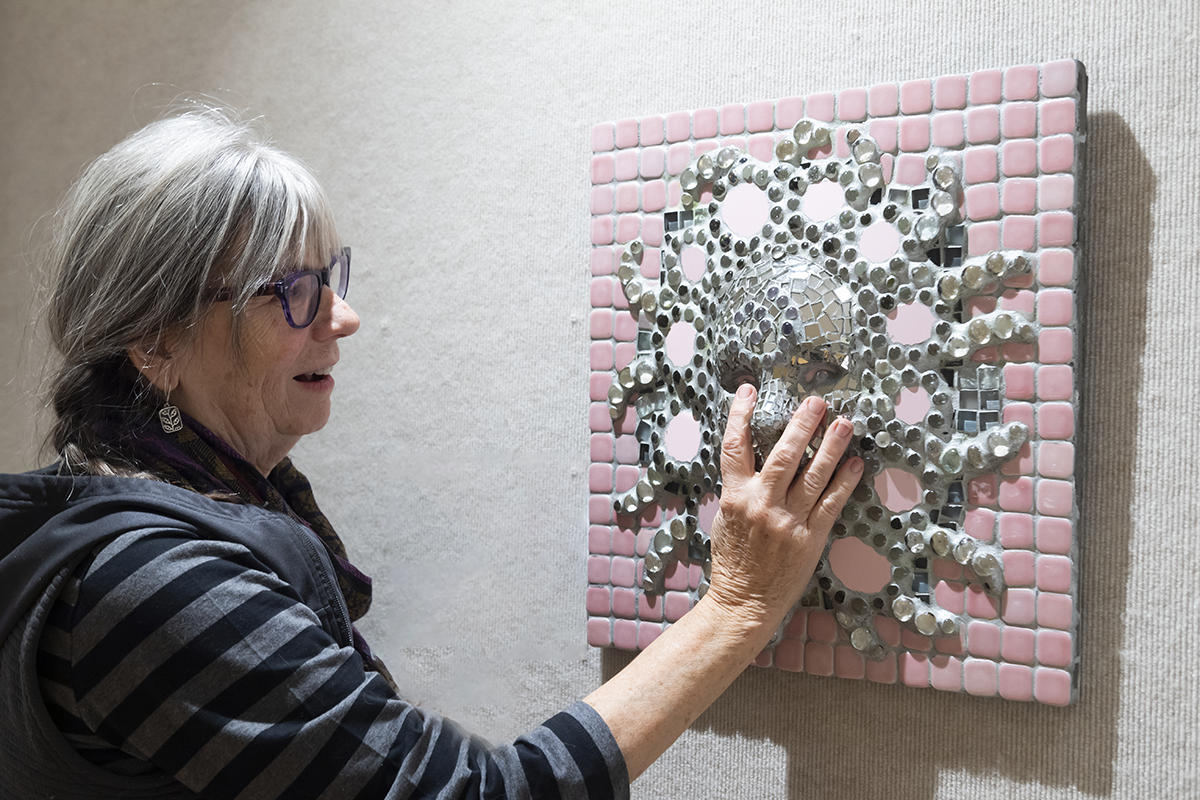 woman at art exhibit feeling the texture of a piece of artwork