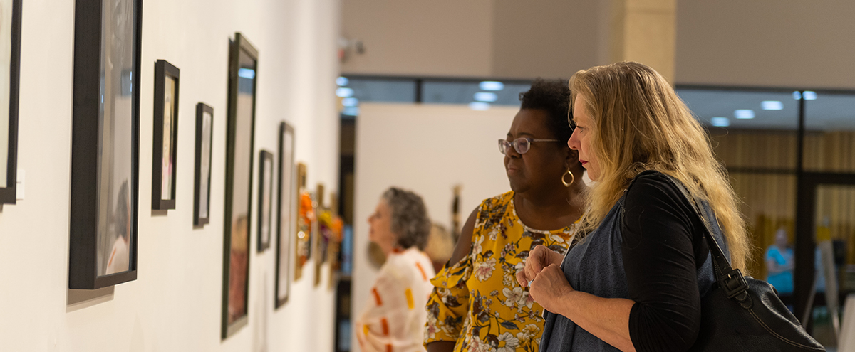 Photo of people viewing artwork displayed in the gallery.