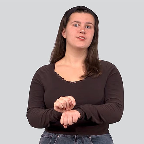 Person wearing a long-sleeve black top making the American Sign Language sign for 'tradition.'