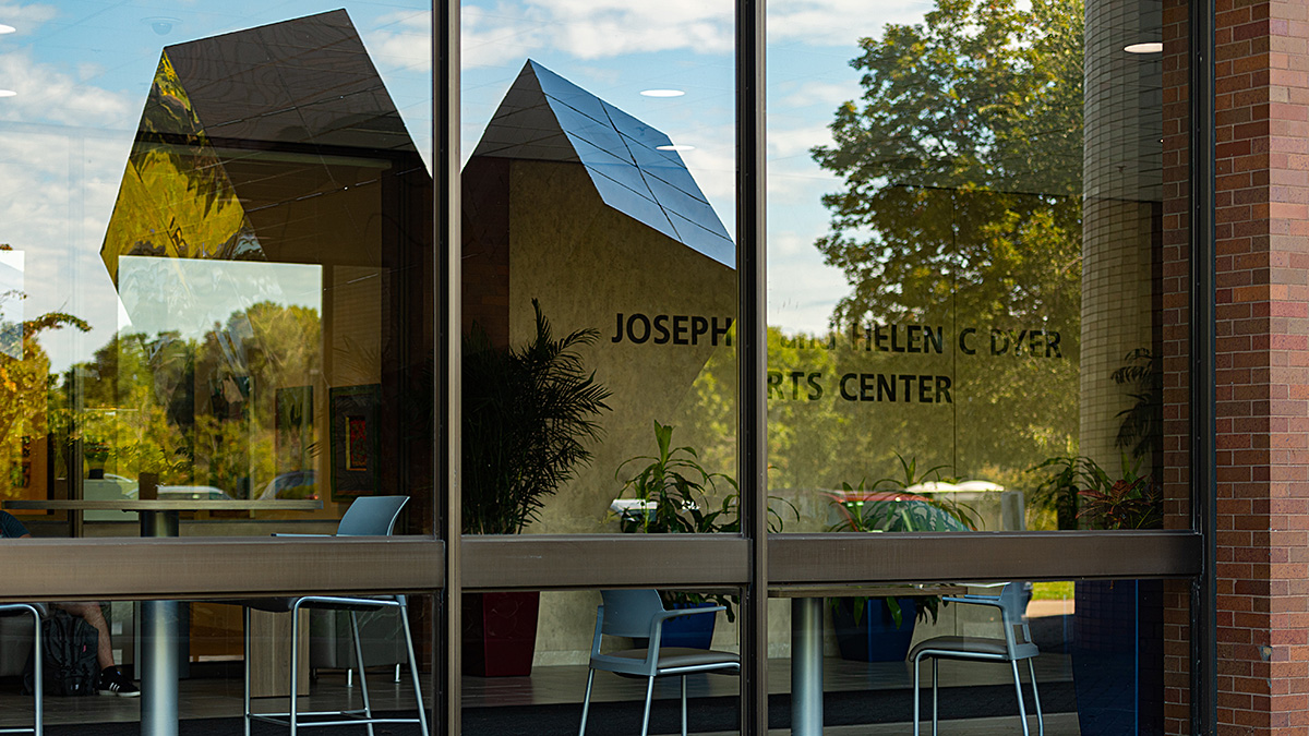 The Split Cube is reflected in the front window of Lyndon B Johnson Hall,  Sept 16, 2019. The cube, which is located on the north side of LBJ, was created by Carl Zollo to commemorate NTID's 10th anniversary in 1978.