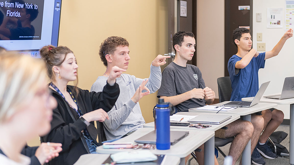Students in a classroom, signing in ASL