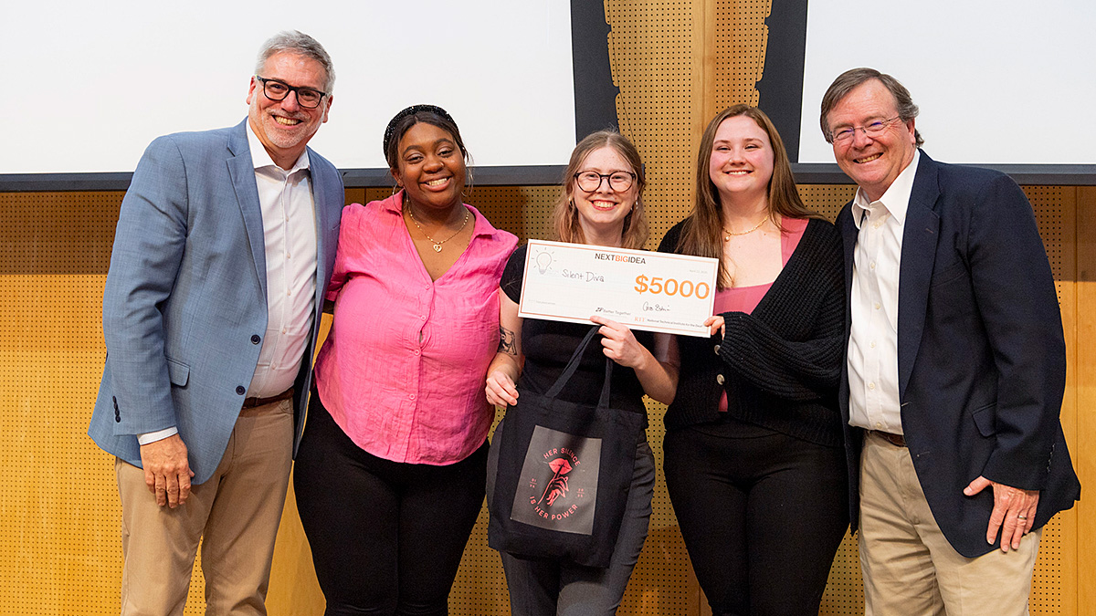 Group of five people standing together, with one person holding a large check for $5000