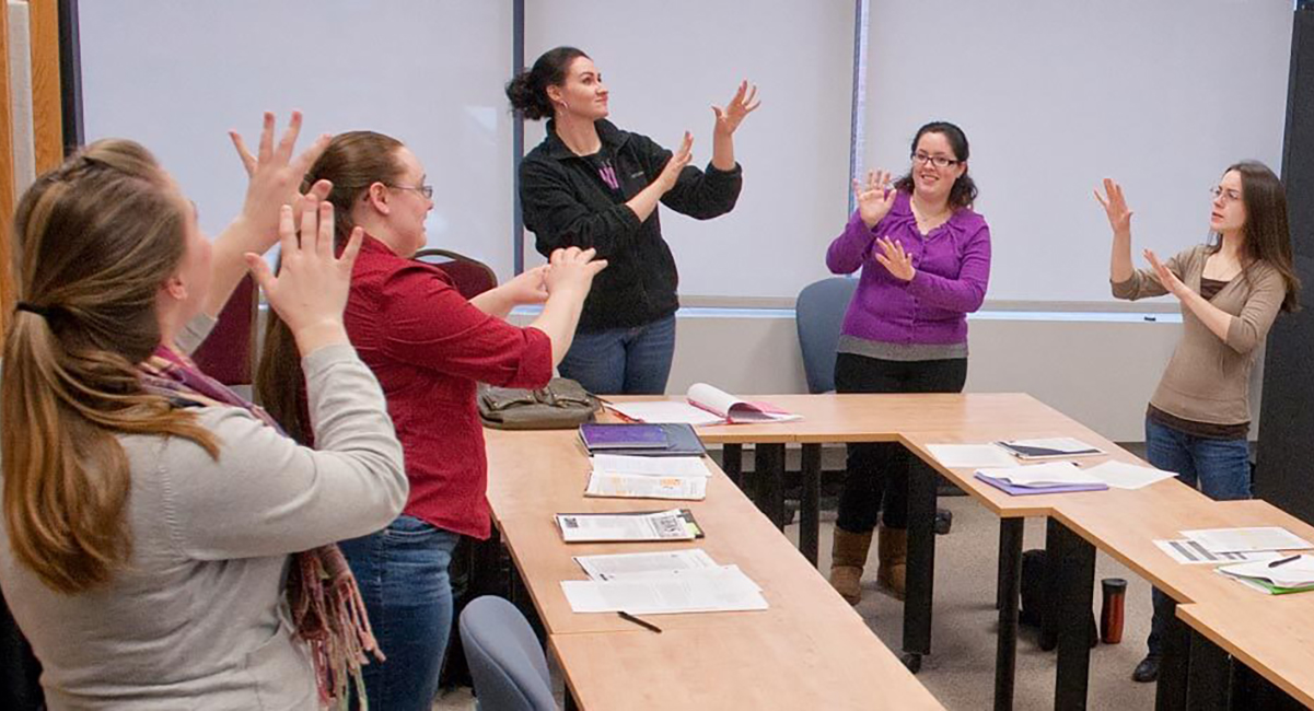 Photo of students in classroom all recreating the sign demonstrated by the instructor