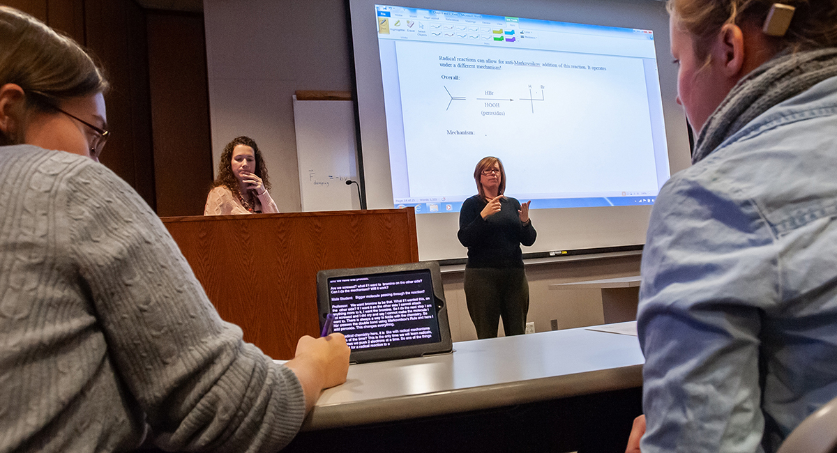 Students looking at C-Print display, teacher and interpreter in background