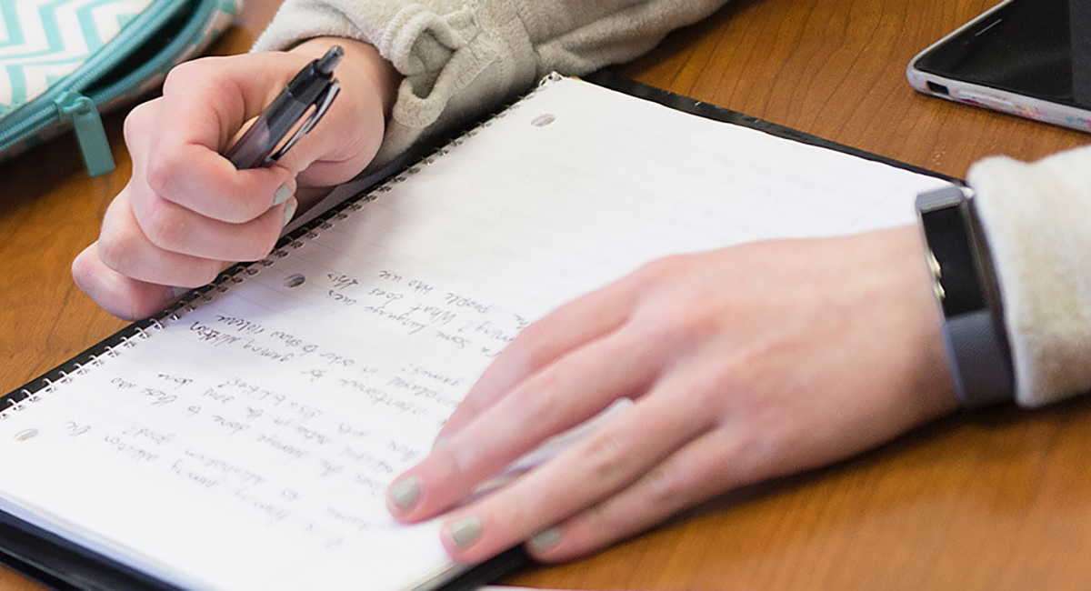 Hand writing over notepads on desk