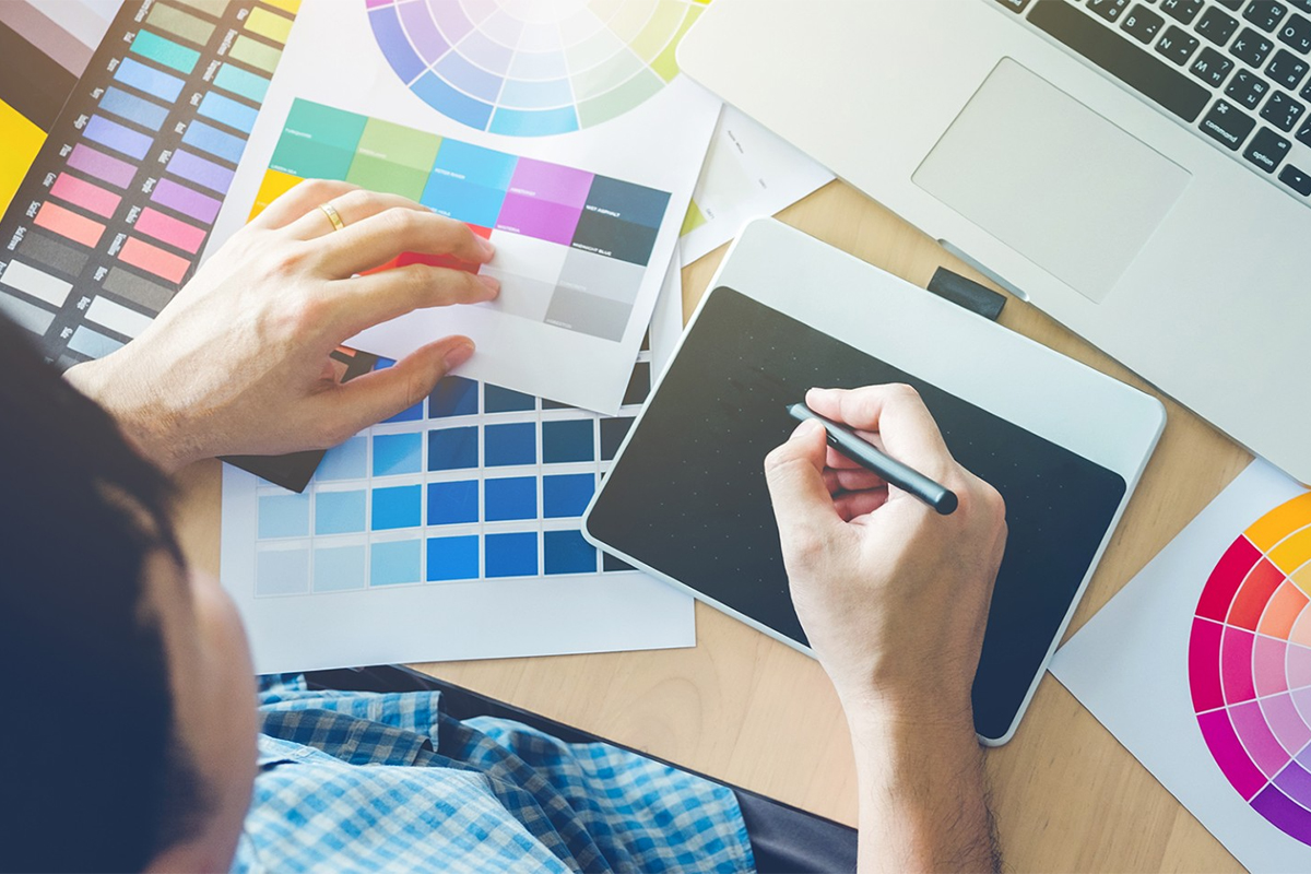 Student working on tablet with color charts on desk