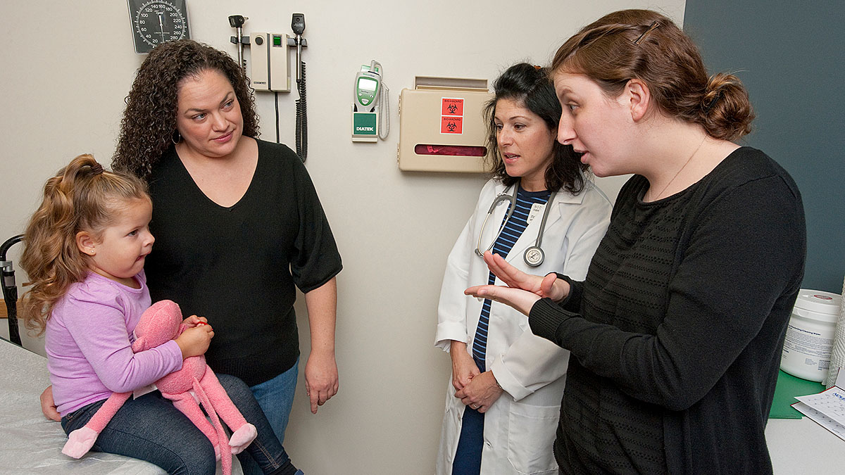 A young patient and her mother communicate with a doctor with an interpreter
