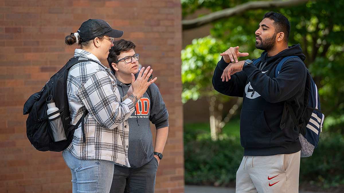 Three students signing with each other
