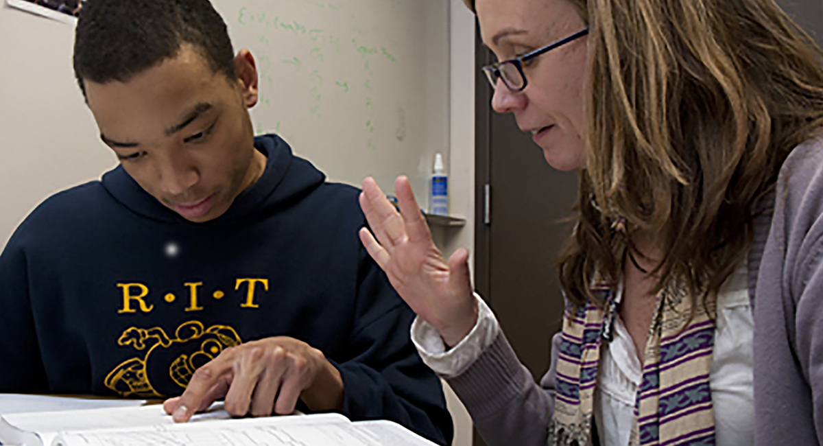 Tutor and student reading from book