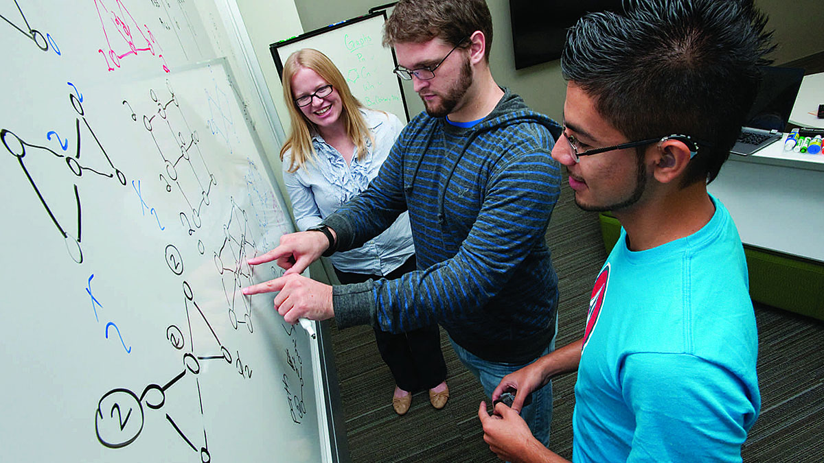 Students examining equation on whiteboard