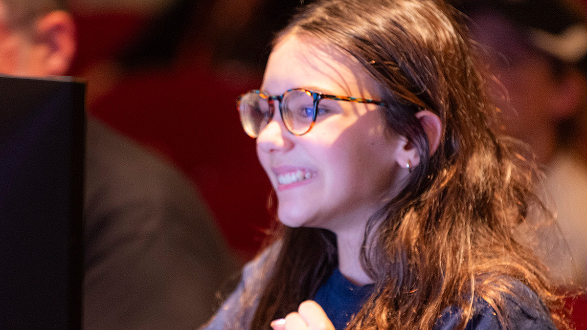 A student smiling and looking at a computer screen