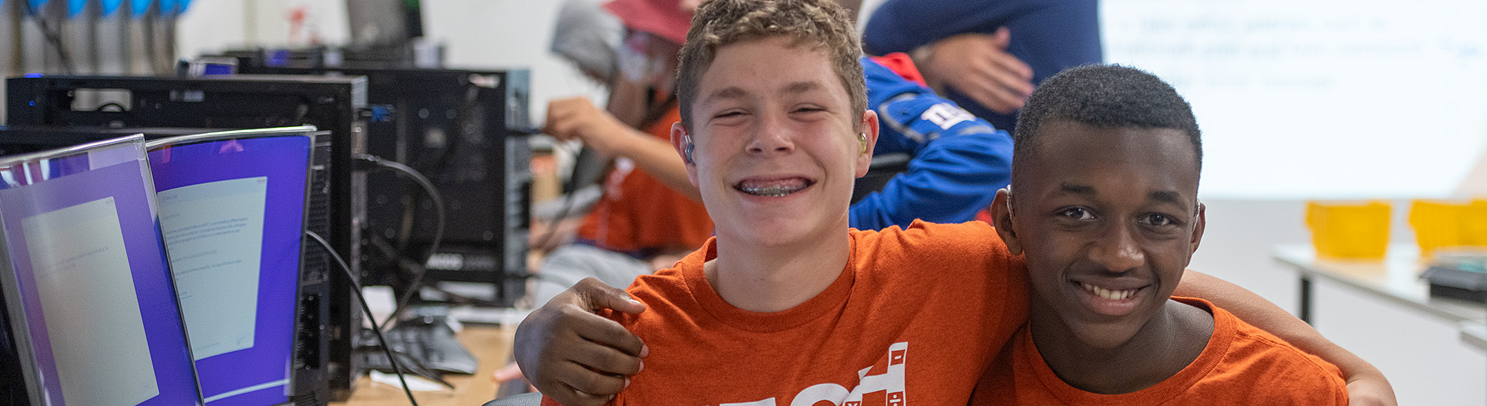 Two students wearing 'Tech Tigers' t-shirts, smiling with their arms around each other's shoulders