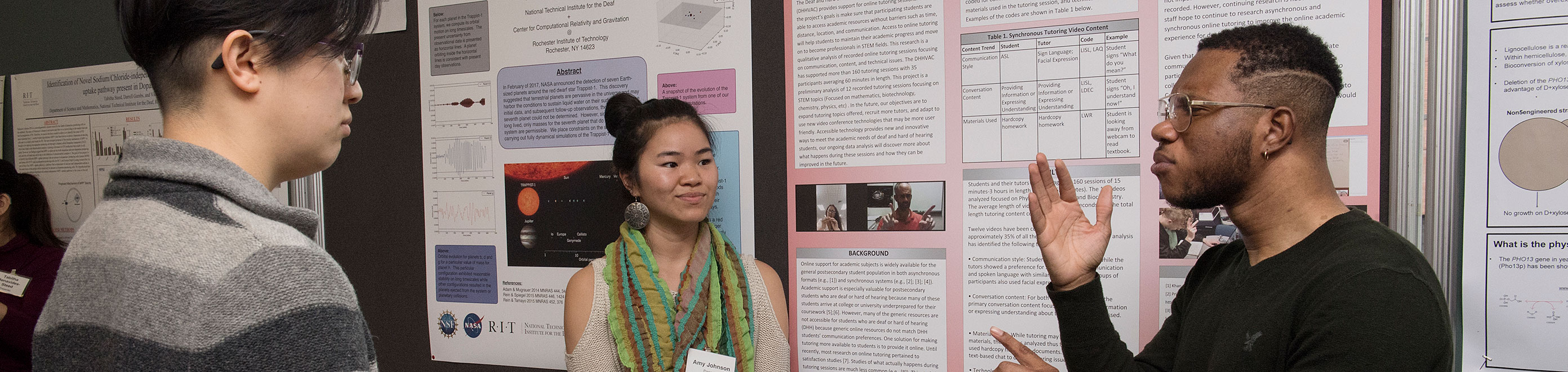 Three students discussing research presented during a poster session