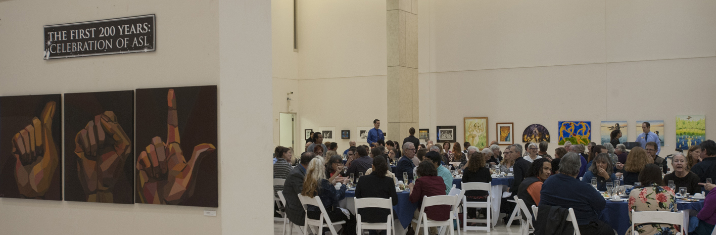 Photo of artwork and people seated at tables at RADSCC Deaf Mute Banquet