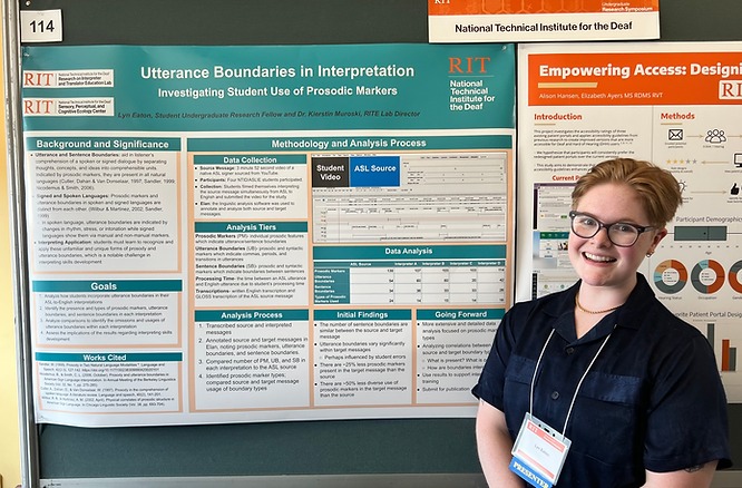 Photo of Lyn standing in front of poster