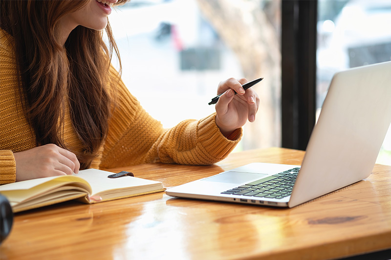 Happy latin girl college student watching distance online learning class, remote university webinar or having talk on laptop video call and use notebook to virtual meeting seminar at home or campus
