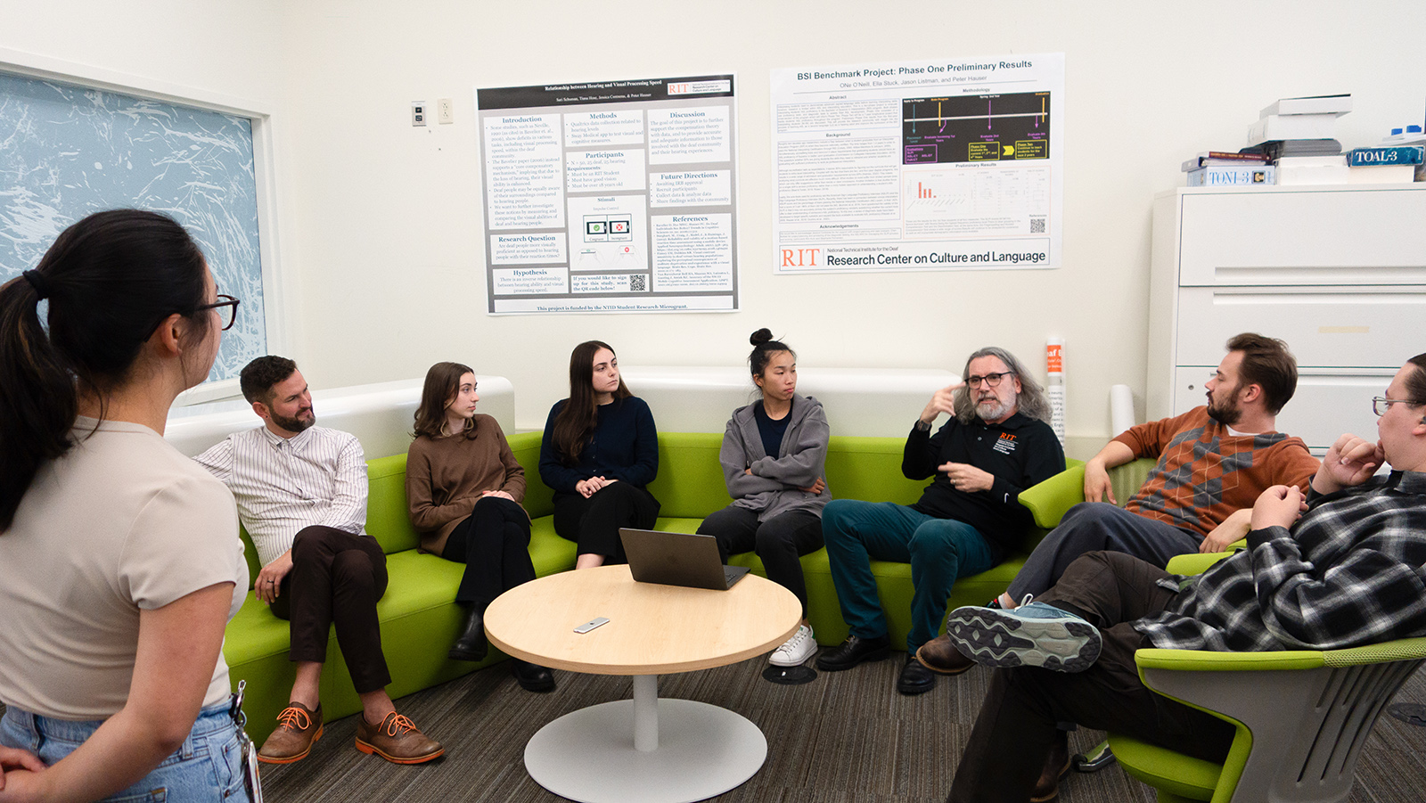 Student standing and conversing with group sitting on couch