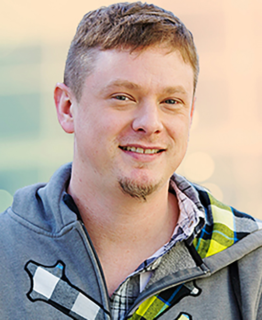 Photo of Andreas Wezel-Peterson man standing outside, blond hair wearing grey hoodie and b&w checked shirt