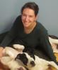 Photo of Jennifer Miller, short dark hair, v-neck sweater, sitting on floor with dog.