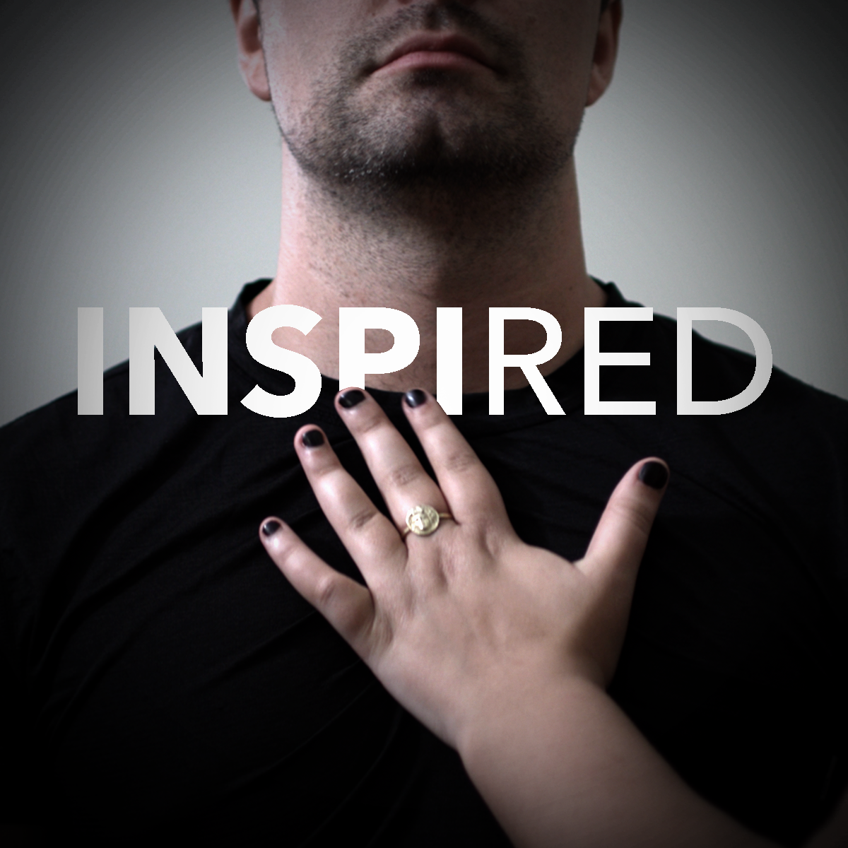 A hand with fingers spread, palm facing a person's chest with a text overlay that reads "Inspired"