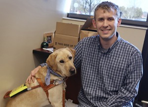 Photo of young man sitting in office with service dog