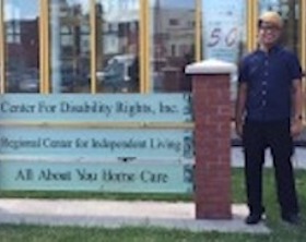 Young man standing near sign for Center for Disability Rights, Inc., Regional Center for Independent Living.