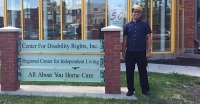 Young man standing near sign for Center for Disability Rights, Inc., Regional Center for Independent Living.