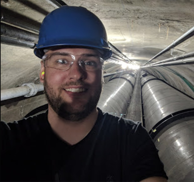 Photo of Ryan Koester, young man in industry tunnel setting wearing safety googles and hardhat