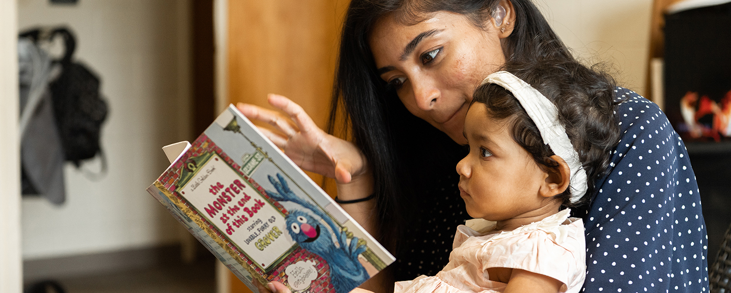 Mother reading and signing book to baby