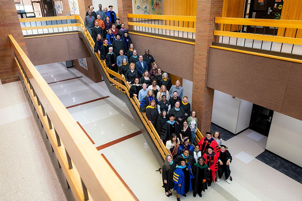 Large group of people posing for a photo on stairs indoors from an elevated angle.