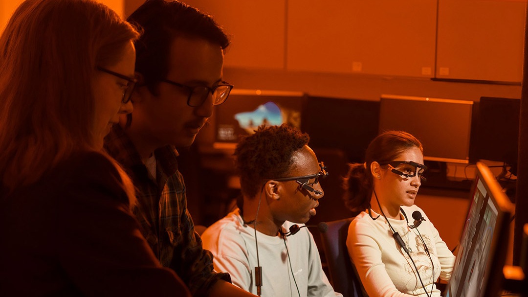 Four students sitting looking at their computers.