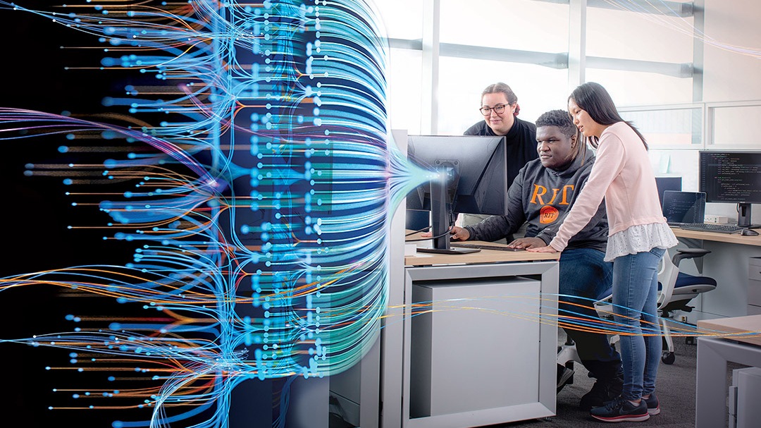Three students looking at computer screen and blue, green, and orange streaks are displayed from computer screen.