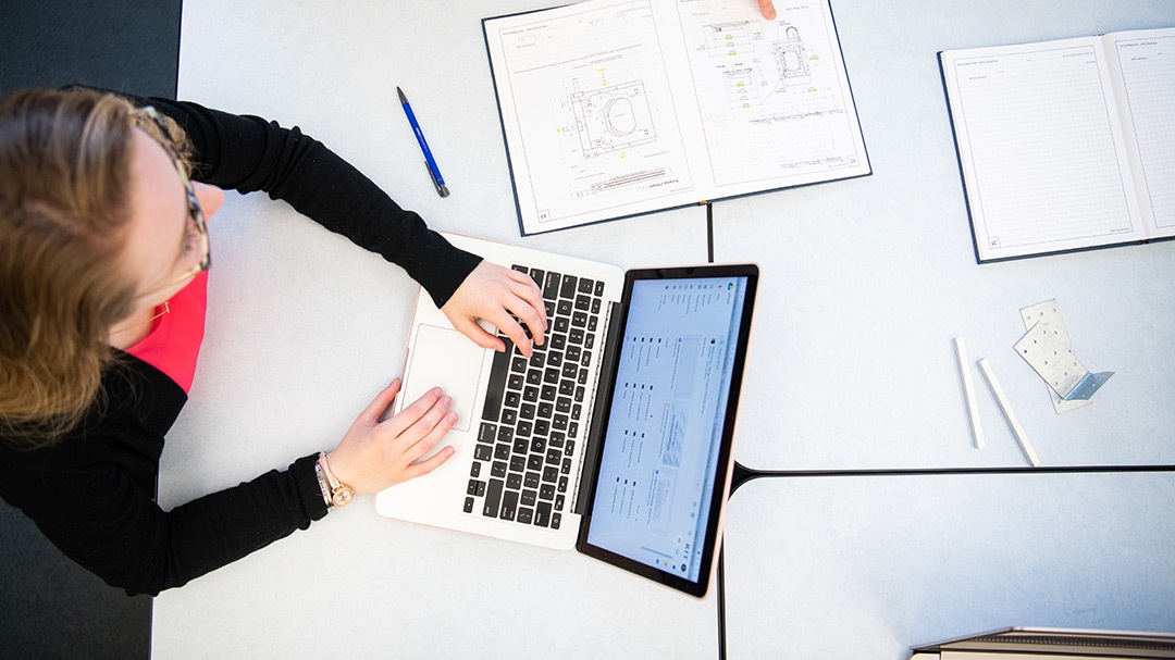 Overhead photo of white woman typing on a laptop.