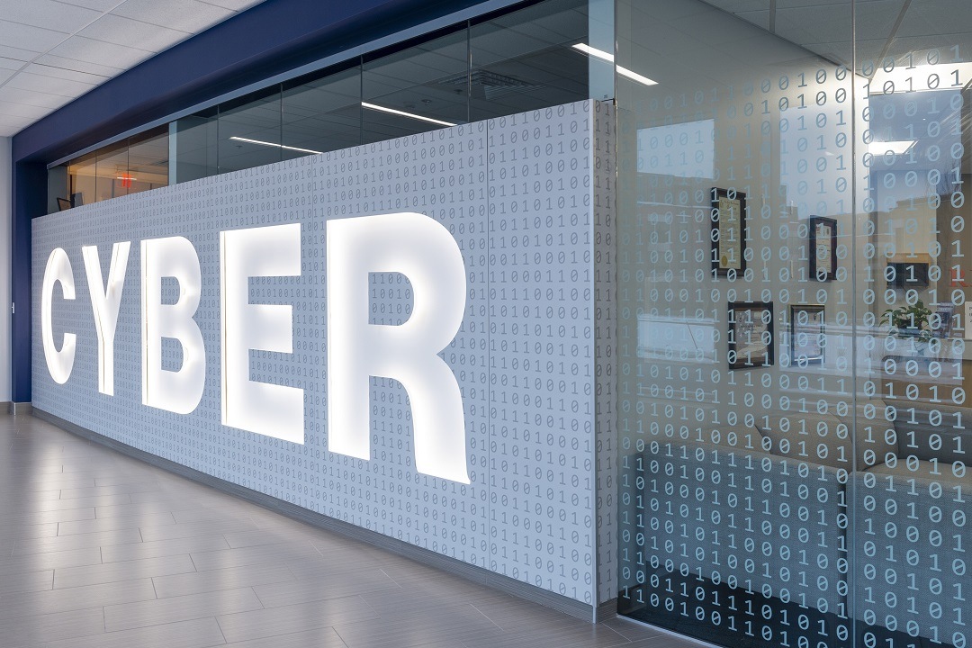 Signage that says "Cyber" in bold white letters is etched on a classroom's glass window with white numbers in the background..