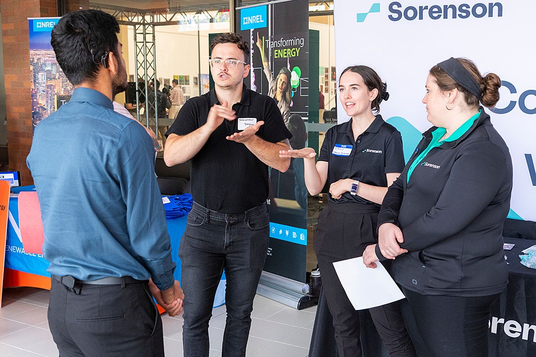 A group of four people at a career fair, with an interpreter facilitating communication between a student and employers