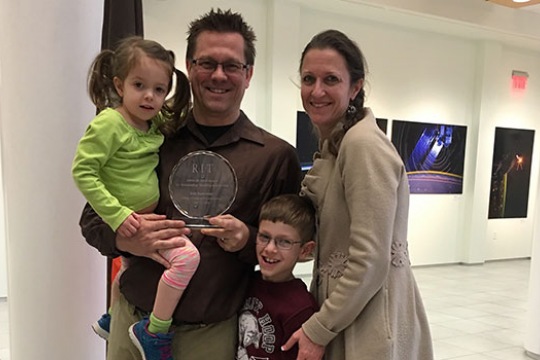 Eric Kunsman and family pose for a picture with award.