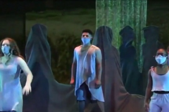 three performers on a stage dressed like spirits.