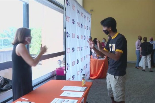 two people at an information table using sign language.
