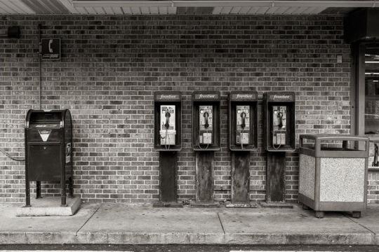 black-and-white bank of payphones outside a convenience store.
