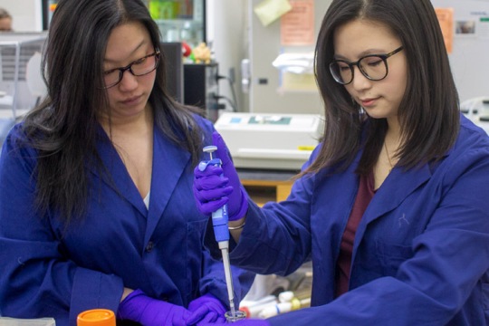 professor observing as a student uses a pipette.