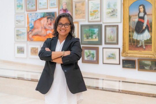 woman posing for photo in front of a wall of artwork.