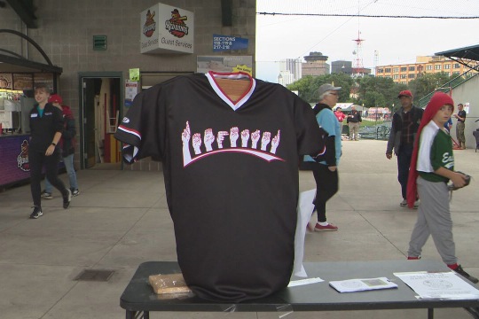 a baseball jersey with hands spelling Rochester in sign language.