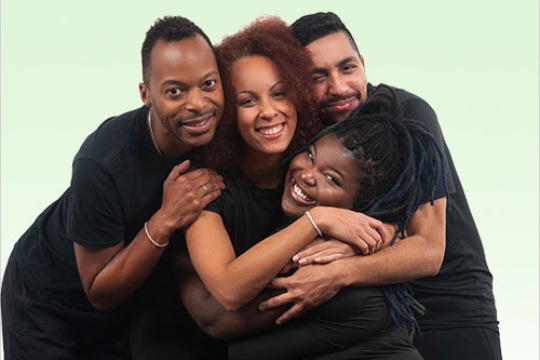 four members of a dance troupe hugging.